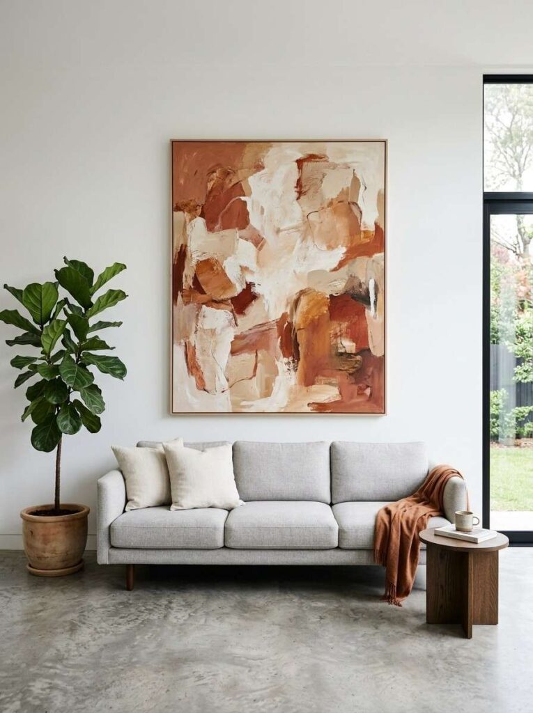 Large abstract canvas art in terracotta tones centered on a white living room wall