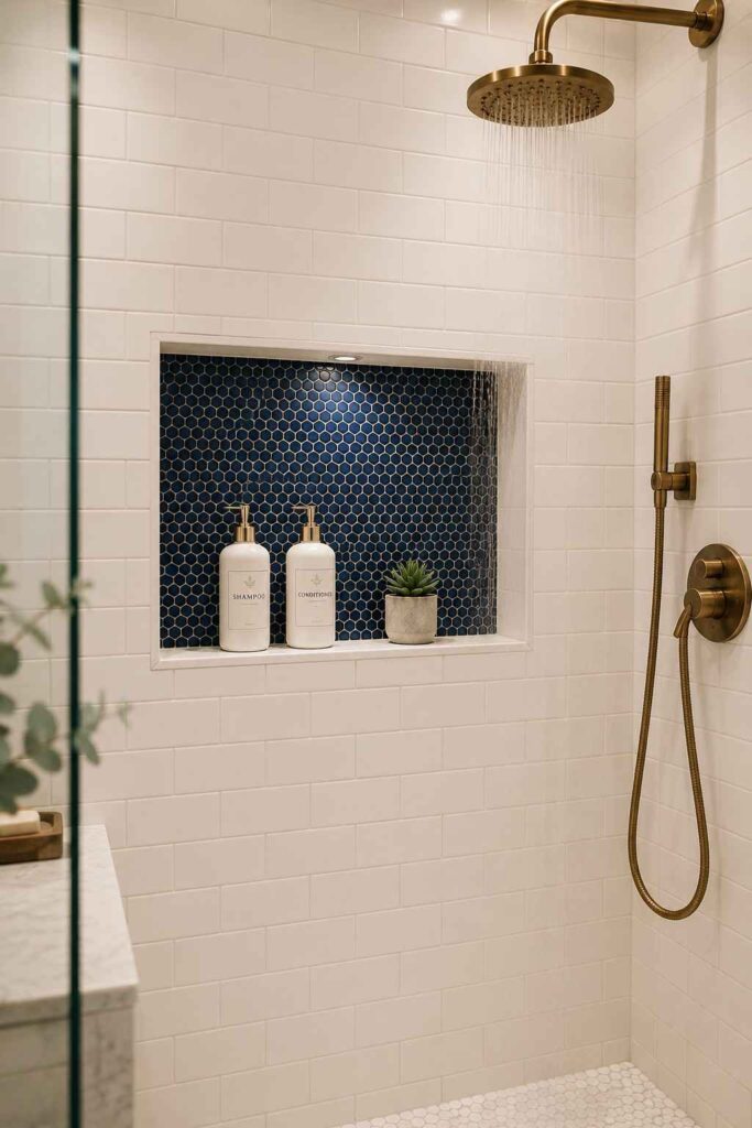 Recessed shower wall niche with navy mosaic tile interior holding shampoo bottles and small succulent plant